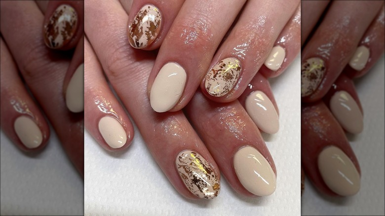 Rounded cream nails with gold leaf details