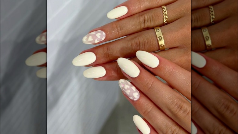 rounded cream-yellow nails with hearts on ring finger