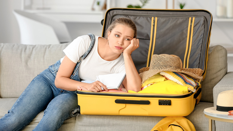 woman sad while packing suitcase