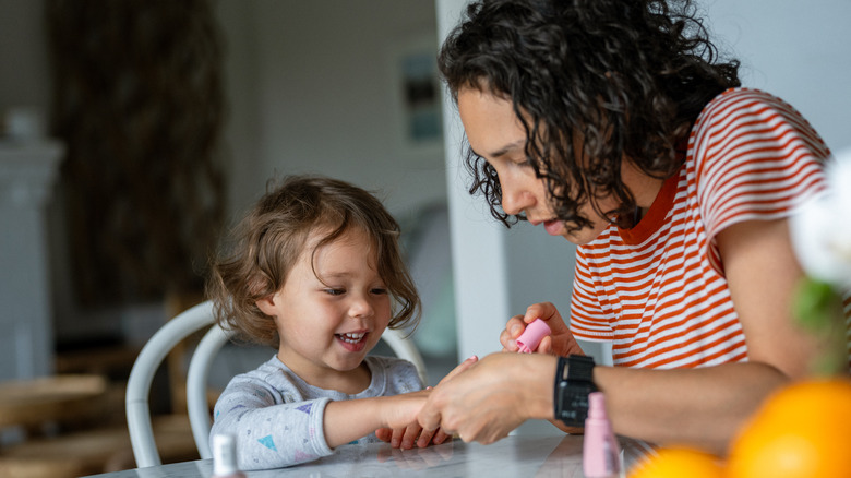 Mother paints child's fingernails 