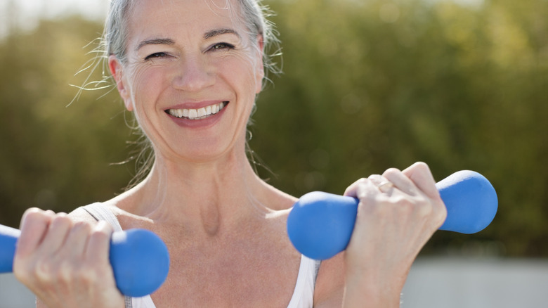 A woman smiling and lifting weights