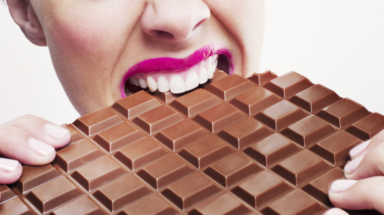 A woman biting into a chocolate bar