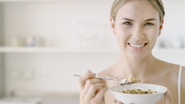 A woman eating yogurt with granola