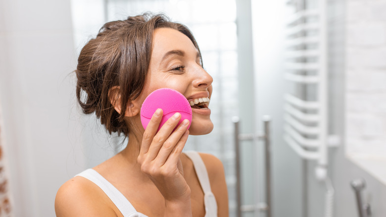 Woman using silicone facial cleansing brush.