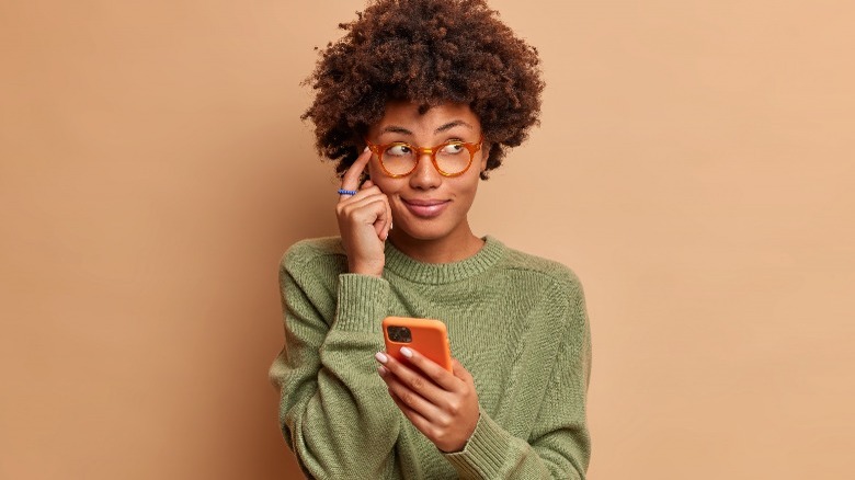 Woman thinking holding a phone