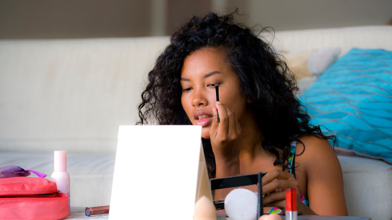 Young woman applies eyeshadow with brush