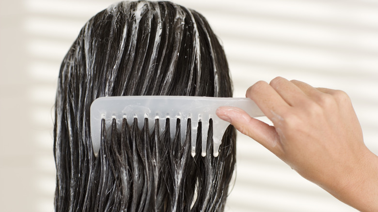Woman combing conditioner through her hair