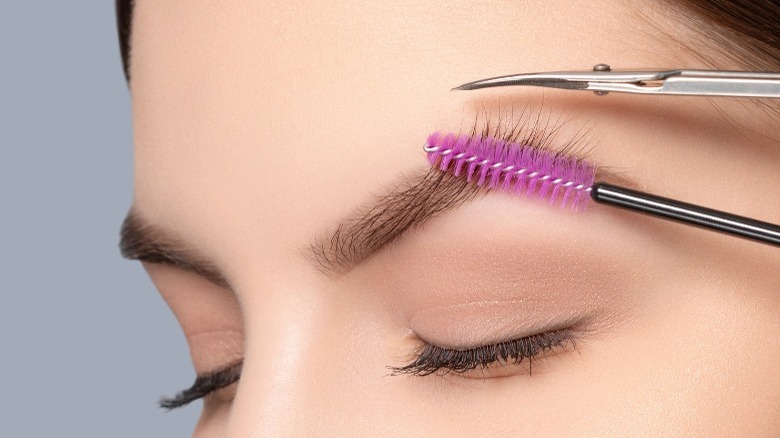 woman with eyebrow brush and scissors