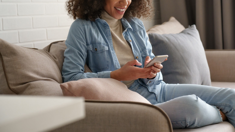 woman using phone on couch