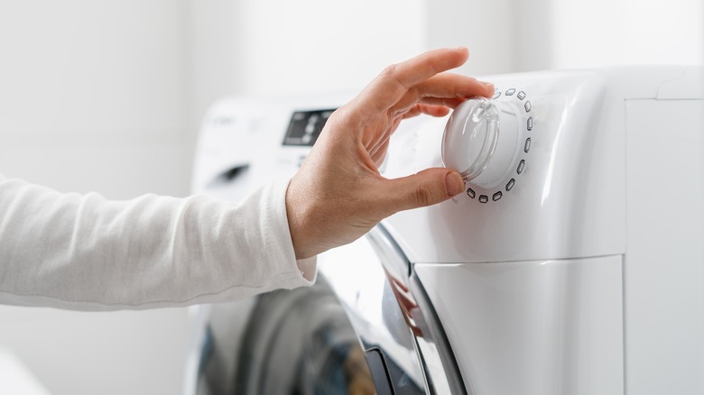 Person turning on the washing machine.