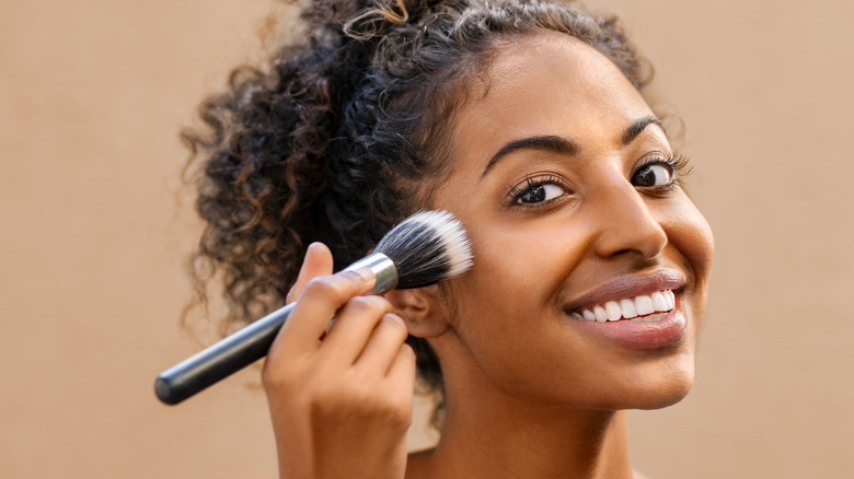 woman applying makeup with brush