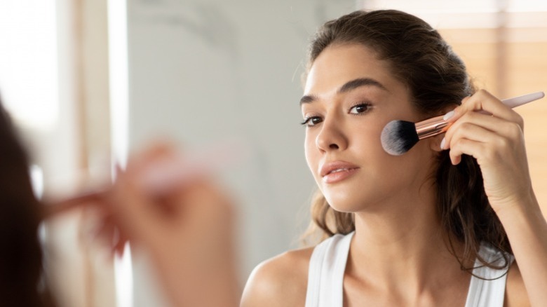 Woman applying makeup in the mirror