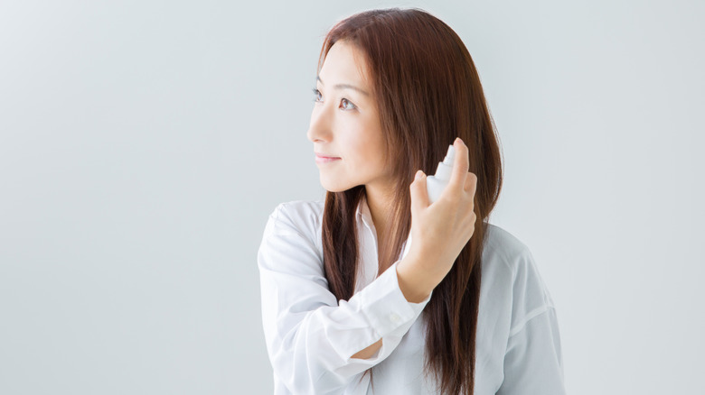 woman applying heat protectant spray