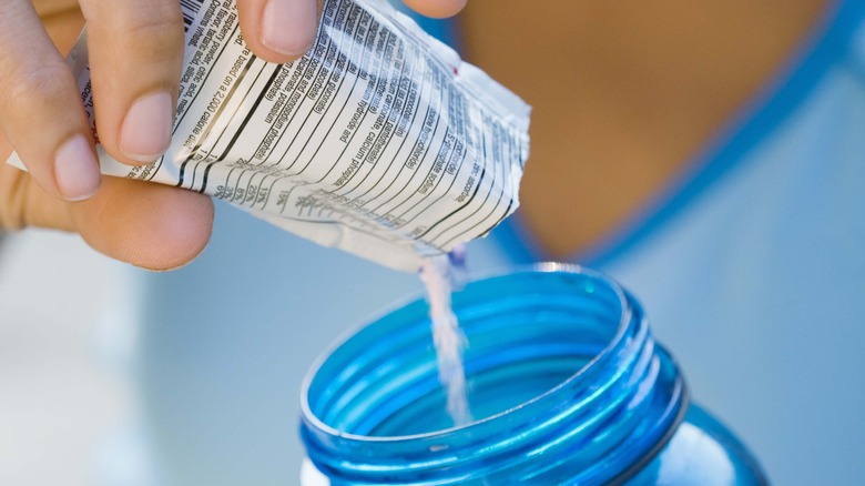 Pouring drink sachet into water bottle