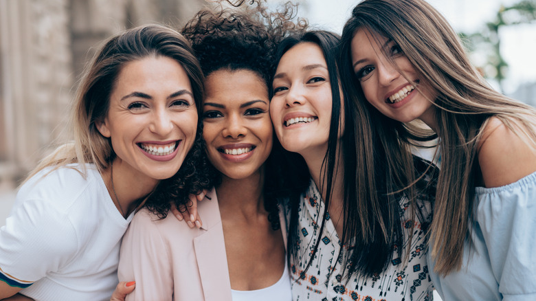 Four diverse female friends smiling 