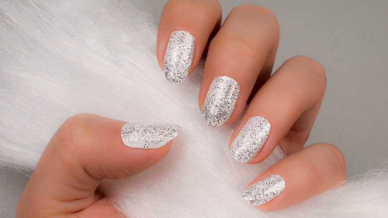 hand with white and glitter nail polishes