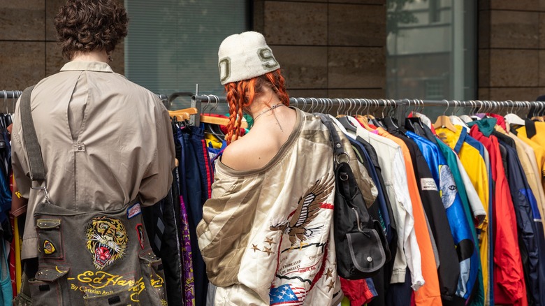 Couple exploring racks of secondhand clothing