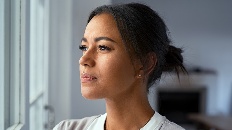 Cautious woman gazing out window