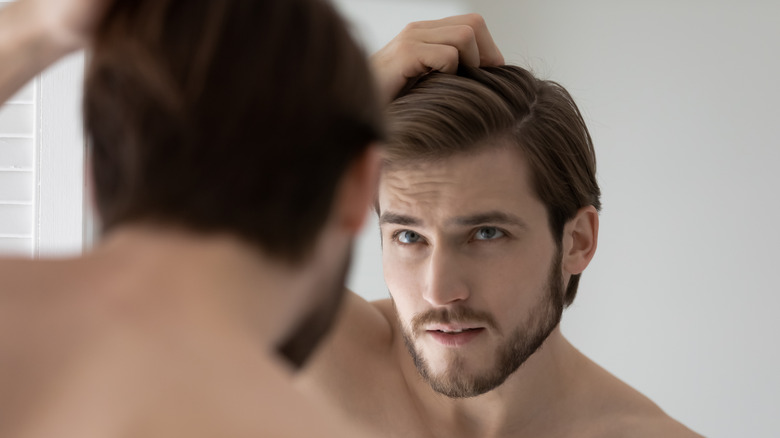Man looking at hair in mirror