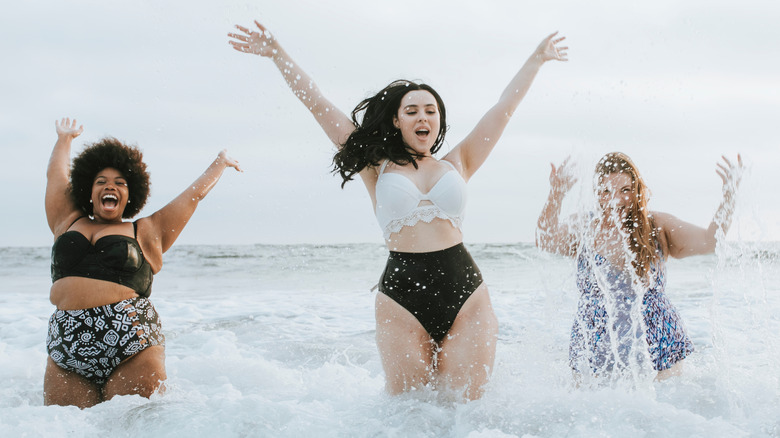 Female friends splashing in ocean