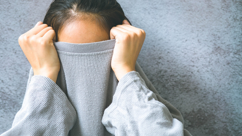 Woman covering her face with her shirt