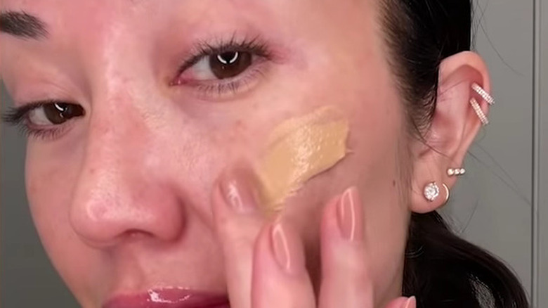 woman applying tinted moisturizer