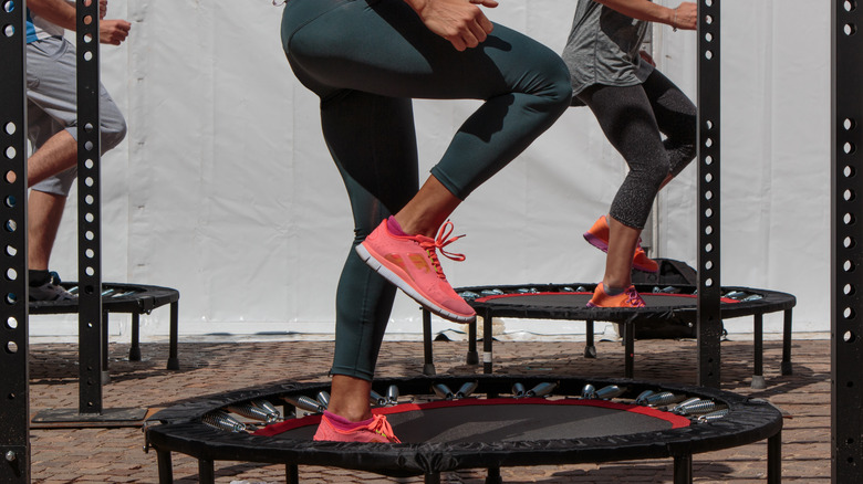 People, waist down, jumping on trampoline