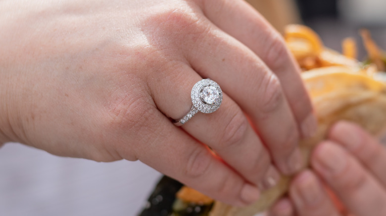 Hand displaying double halo diamond ring