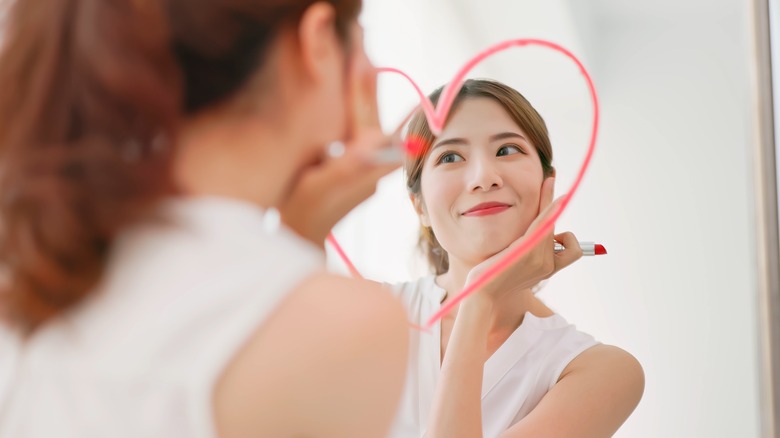 woman drawing heart in mirror