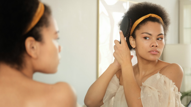 Woman looking at her curls in the mirror.