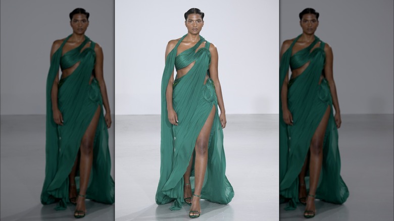 Model walking runway in green dress