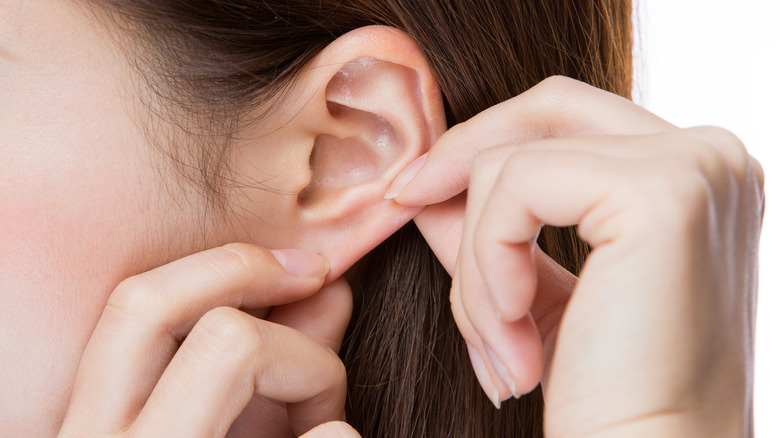 Woman examines ear piercings 