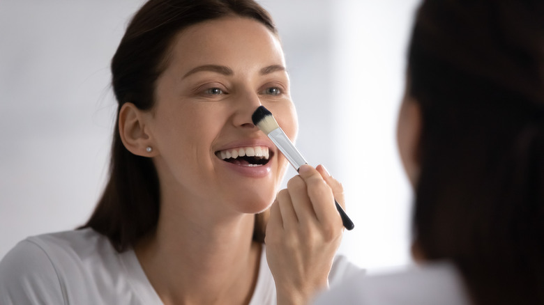 Woman putting bronzer on nose