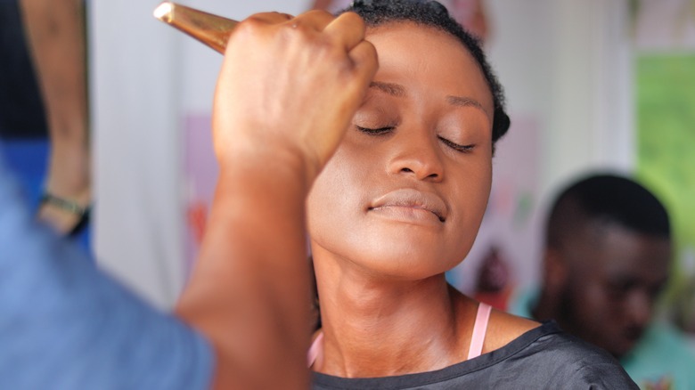 Applying bronzer to woman's hairline