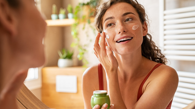 Woman applying moisturizer 