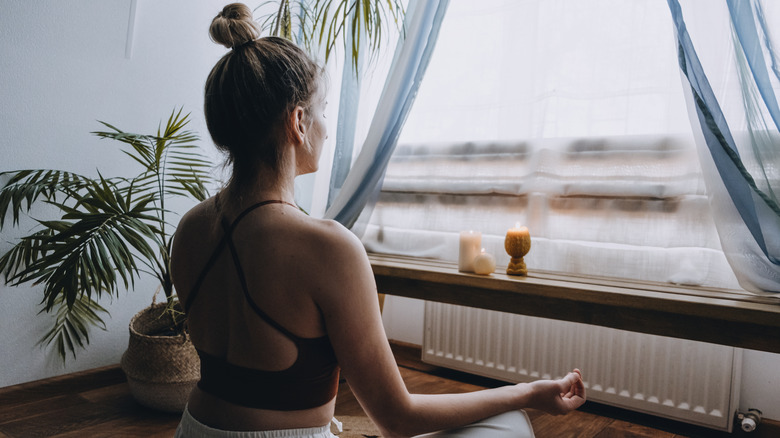 woman meditating by window