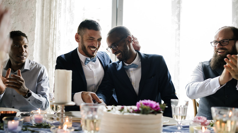 Gay couple cutting wedding cake