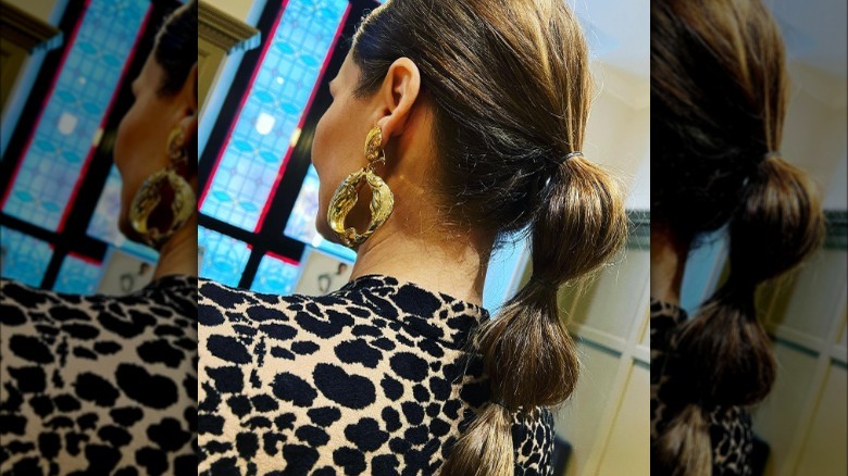 Woman wears large gold earrings 