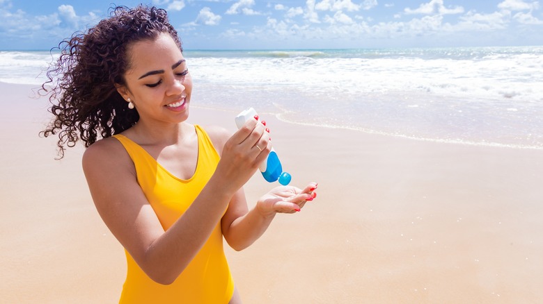 woman applying sunscreen at beach 