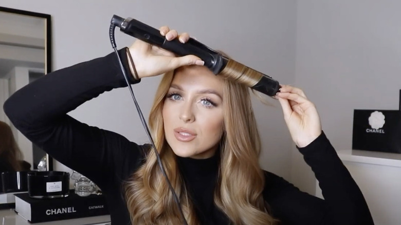 woman curling hair with iron