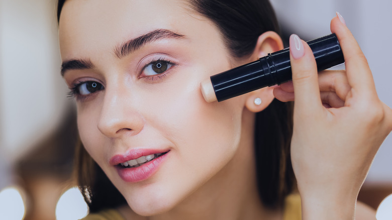 woman applying concealer to face