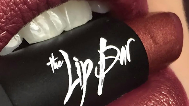 Lip Bar red lipstick held by teeth