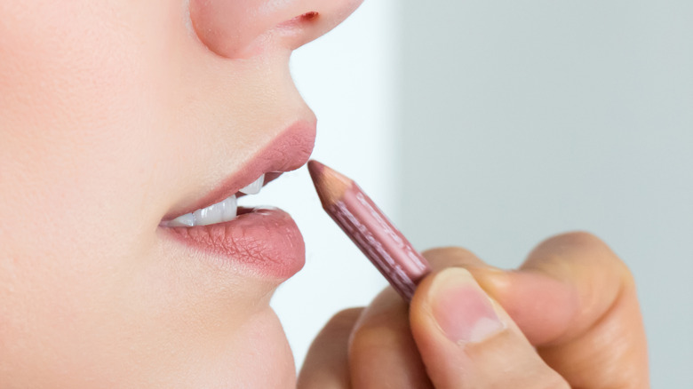 woman applying nude lipliner on lips 