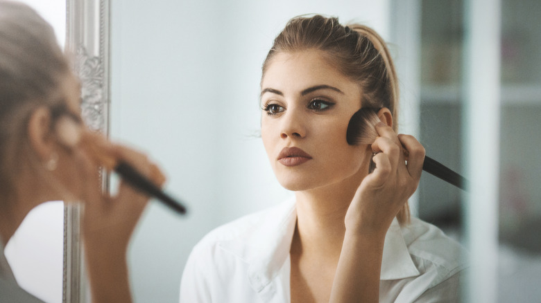 woman applying makeup in mirror