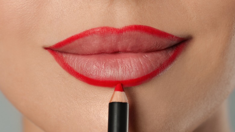 closeup of lips applying red lip liner