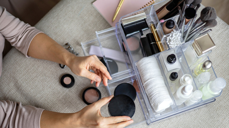 Woman sorts beauty and skincare products 