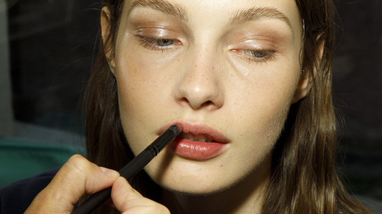 A woman having lipstick applied