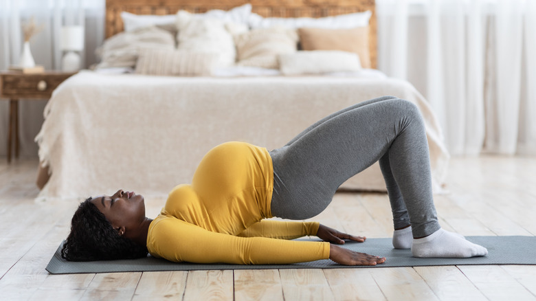 pregnant woman doing a hip stretch on the floor