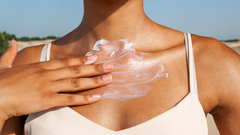 woman applying sunscreen on décolletage