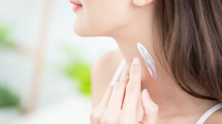 woman applying sunscreen on neck